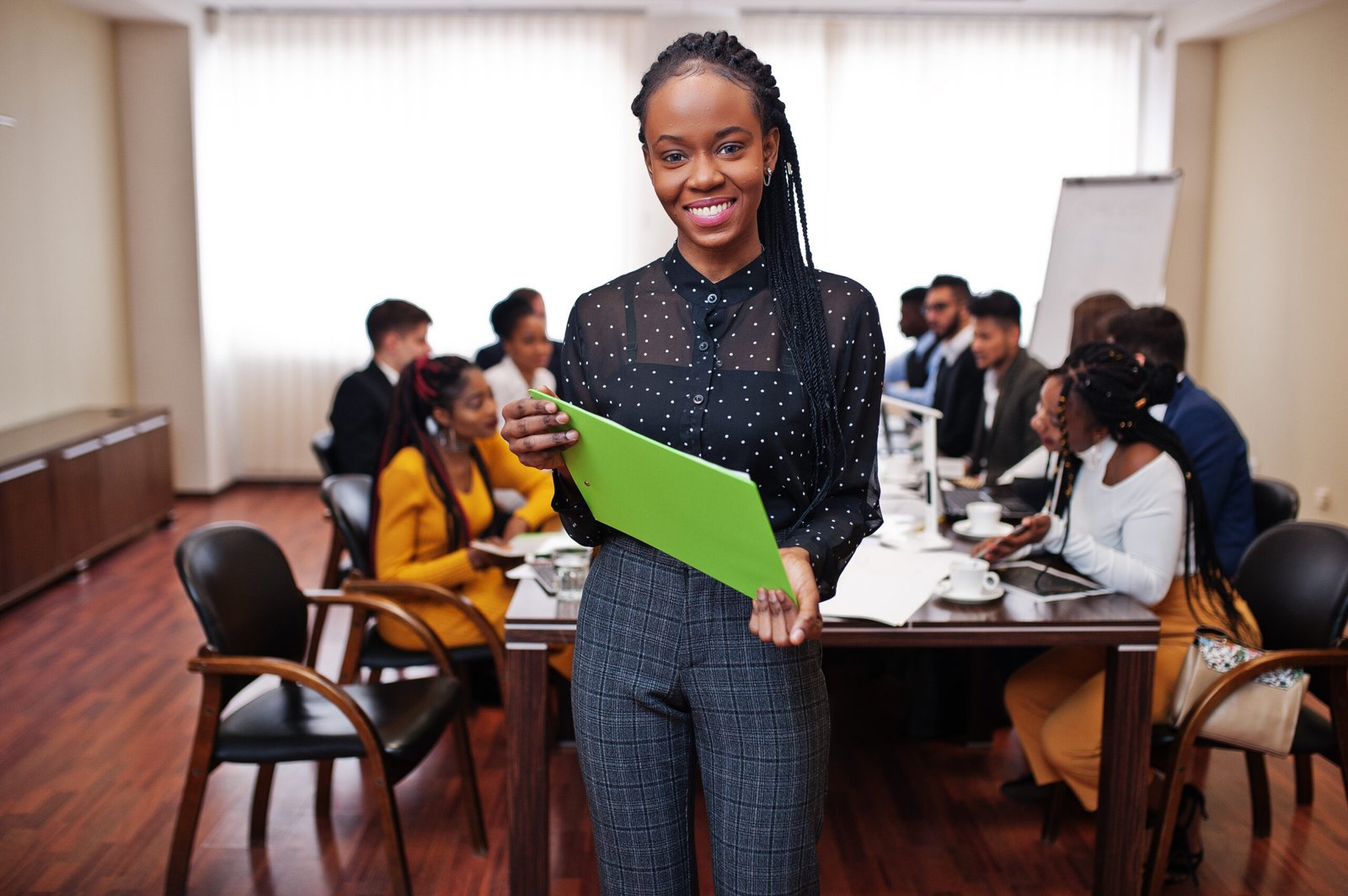 Face of handsome african business woman, holding clipboard on the background of business peoples multiracial team meeting, sitting in office table.